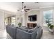Living room featuring a large sectional sofa, television, and sliding glass doors to the patio at 13561 W Montebello Ave, Litchfield Park, AZ 85340