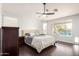 Bright main bedroom with wood floors, ceiling fan, and a large window overlooking the pool at 13561 W Montebello Ave, Litchfield Park, AZ 85340