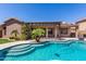 Inviting backyard pool featuring a covered patio, travertine decking, and lush landscaping; perfect for relaxation at 13561 W Montebello Ave, Litchfield Park, AZ 85340