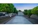 Backyard featuring a concrete path lined with manicured trees, leading to a storage shed with a nearby patio and pool at 1532 N Ogden --, Mesa, AZ 85205