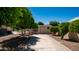 Wide driveway leading to a backyard with mature trees, storage shed, and lush landscaping at 1532 N Ogden --, Mesa, AZ 85205