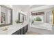 Bright bathroom with dual sinks, framed mirrors and a tub under a window at 1532 N Ogden --, Mesa, AZ 85205
