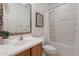 Bright bathroom featuring a vanity, patterned-framed mirror, and a shower-tub combo with white tile surround at 1634 W Red Bird Rd, Phoenix, AZ 85085