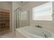 Bright bathroom boasts a luxurious soaking tub, glass-enclosed shower, and ample natural light at 1634 W Red Bird Rd, Phoenix, AZ 85085