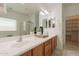 Bathroom features dual sinks with wood cabinetry, a large mirror, and a glass shower enclosure at 1634 W Red Bird Rd, Phoenix, AZ 85085