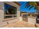 Backyard area featuring a built-in stainless steel grill and travertine stone patio surrounded by lush landscaping at 1787 E Sattoo Way, Queen Creek, AZ 85140