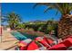 Backyard pool area with lounge chairs, a built-in outdoor kitchen, and lush tropical landscaping at 1787 E Sattoo Way, Queen Creek, AZ 85140