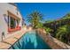 Backyard pool area with lush landscaping, built-in outdoor kitchen, patio seating, and a travertine stone patio at 1787 E Sattoo Way, Queen Creek, AZ 85140