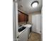 Well-lit laundry room with a washer, dryer, upper cabinets, tile floor, and white painted door to outside at 1810 N Mcdonald St, Casa Grande, AZ 85122