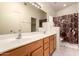 Primary bathroom featuring double sinks, wood cabinets, and shower with curtain at 18221 N 49Th Pkwy, Glendale, AZ 85308