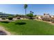 Well-maintained front yard with green grass, flower bushes, and a moving truck at 18221 N 49Th Pkwy, Glendale, AZ 85308