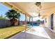 Inviting backyard featuring a refreshing pool, covered patio with ceiling fans, grassy area, and mature palm trees at 1829 E Decatur St, Mesa, AZ 85203