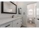 Bathroom boasts a white vanity with dark fixtures, contrasting dark framed mirror, and an adjacent open-concept toilet room at 2552 E Silverwood Dr, Phoenix, AZ 85048