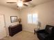 Neutral bedroom with a ceiling fan, window with blinds, a dark dresser and a comfortable black chair at 25935 W Potter Dr, Buckeye, AZ 85396