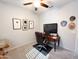 Comfortable home office featuring a computer desk, executive chair, mounted TV, and carpet flooring at 25935 W Potter Dr, Buckeye, AZ 85396
