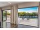 Open doors to backyard featuring a pool, lounge chairs, covered patio, and lush landscaping at 26099 N 88Th Way, Scottsdale, AZ 85255