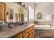 Elegant bathroom featuring tile countertops, natural wood cabinets, and a large soaking tub at 2641 E Birchwood Pl, Chandler, AZ 85249