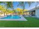 Lush backyard showcasing a pool with a water feature, covered patio, and outdoor kitchen at 26879 N 100Th Ln, Peoria, AZ 85383