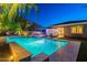 Backyard swimming pool with tanning ledge, lush landscaping and patio furniture at twilight at 26879 N 100Th Ln, Peoria, AZ 85383