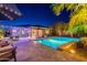 Backyard swimming pool with travertine tile deck, lush landscaping and patio furniture at twilight at 26879 N 100Th Ln, Peoria, AZ 85383