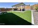 Spacious backyard with artificial turf, a covered patio area, and mature trees for shade at 27636 W Runion Dr, Buckeye, AZ 85396