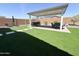 Serene backyard with manicured lawn, covered patio with outdoor kitchen and dining area at 27636 W Runion Dr, Buckeye, AZ 85396