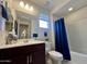 Well-lit bathroom with vanity, mirror, and a shower-tub combo with blue curtain at 27636 W Runion Dr, Buckeye, AZ 85396