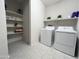 Bright laundry room with modern washer and dryer and ample shelving for storage at 27636 W Runion Dr, Buckeye, AZ 85396