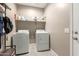 Functional laundry room with modern washer and dryer units plus storage shelves for supplies at 37008 N Hinterwald Way, San Tan Valley, AZ 85143