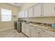 Modern laundry room with white cabinets, granite countertops and stainless steel washer and dryer at 5122 S Miller Pl, Chandler, AZ 85249