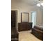 Bedroom with tile floors, open closet, dresser with mirror and open door to bathroom at 6631 E Rhodes St, Mesa, AZ 85215