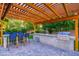 Outdoor kitchen and dining area beneath a pergola, featuring lush green landscaping at 6831 E Presidio Rd, Scottsdale, AZ 85254