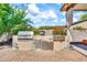 Outdoor grilling area featuring a built-in grill, sink, storage, and a stone-accented base, set on a brick patio at 747 E Meadow Ln, Phoenix, AZ 85022