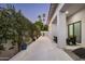 Backyard view with a white brick pathway, lush greenery, and exterior wall of home with black framed windows at 7614 E Cactus Wren Rd, Scottsdale, AZ 85250