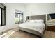 Bright bedroom featuring a large bed with a gray headboard, hardwood floors, and a view to the outside at 7614 E Cactus Wren Rd, Scottsdale, AZ 85250