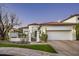Elegant home featuring a red tile roof, gated courtyard, three car garage, and desert landscaping at 7614 E Cactus Wren Rd, Scottsdale, AZ 85250