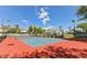 Outdoor tennis court featuring blue and red surface with lights, surrounded by lush landscaping and neighborhood homes at 7614 E Cactus Wren Rd, Scottsdale, AZ 85250