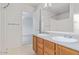Bright bathroom with double sinks, wood cabinets, large mirror, and view into bedroom at 8924 E Portobello Ave, Mesa, AZ 85212