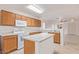 Open kitchen with wood cabinets, white appliances, and a breakfast bar island with views to the living area at 8924 E Portobello Ave, Mesa, AZ 85212