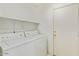 Bright laundry room features both washer and dryer units and overhead shelf storage at 8924 E Portobello Ave, Mesa, AZ 85212