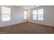 This bedroom has three windows letting in lots of natural light and neutral-colored carpeted floors at 1036 E Magnum Rd, San Tan Valley, AZ 85140