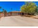 Single story brick home featuring a two-car garage, gated driveway, and mature trees for added privacy at 1170 E Carmen St, Tempe, AZ 85283