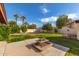 Lush backyard featuring a grass lawn, mature trees, and a brick-lined fire pit, perfect for outdoor enjoyment at 12899 W Pasadena Ave, Litchfield Park, AZ 85340