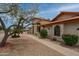 Charming single-story home with a terra cotta roof, arched windows, a desert landscape, and mature trees at 12899 W Pasadena Ave, Litchfield Park, AZ 85340