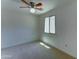 This bedroom features neutral carpet, a ceiling fan, and a window at 1423 W Joan De Arc Ave, Phoenix, AZ 85029