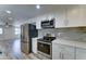 Well-lit kitchen boasts stainless steel appliances, white cabinets, and modern gray backsplash at 1423 W Joan De Arc Ave, Phoenix, AZ 85029