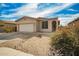 Single-story tan home featuring low maintenance desert landscaping and two car garage at 15134 N 138Th Ln, Surprise, AZ 85379