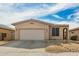 Tan single-story home featuring a two-car garage, desert landscaping, and an arched entryway at 15134 N 138Th Ln, Surprise, AZ 85379