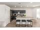 Modern kitchen features an island with barstool seating, granite countertops, stainless steel appliances, and wood-look flooring at 15134 N 138Th Ln, Surprise, AZ 85379