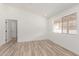 Bright bedroom with wood-look tile flooring, large window, and fresh white paint at 1633 E Beverly Ln, Phoenix, AZ 85022